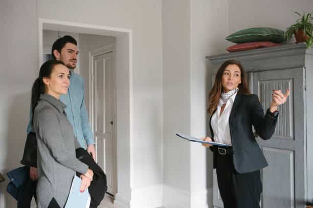 Jeune femme agent immobilier qui fait visiter un appartement à un jeune couple